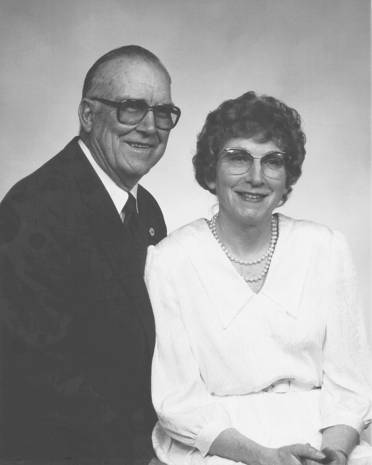 Black and white photo of an older couple posing together against a plain background