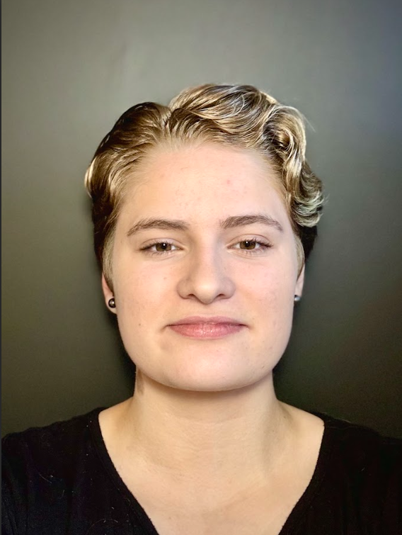 Person with short blonde hair against a plain background