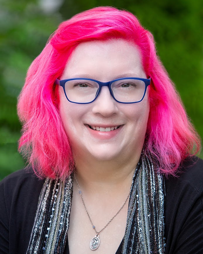 Person with bright pink hair and blue glasses against a green background