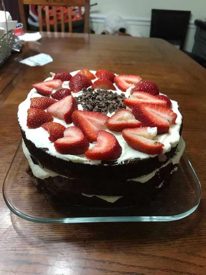 A no sugar no flour cake with strawberries on a glass plate on a wooden table