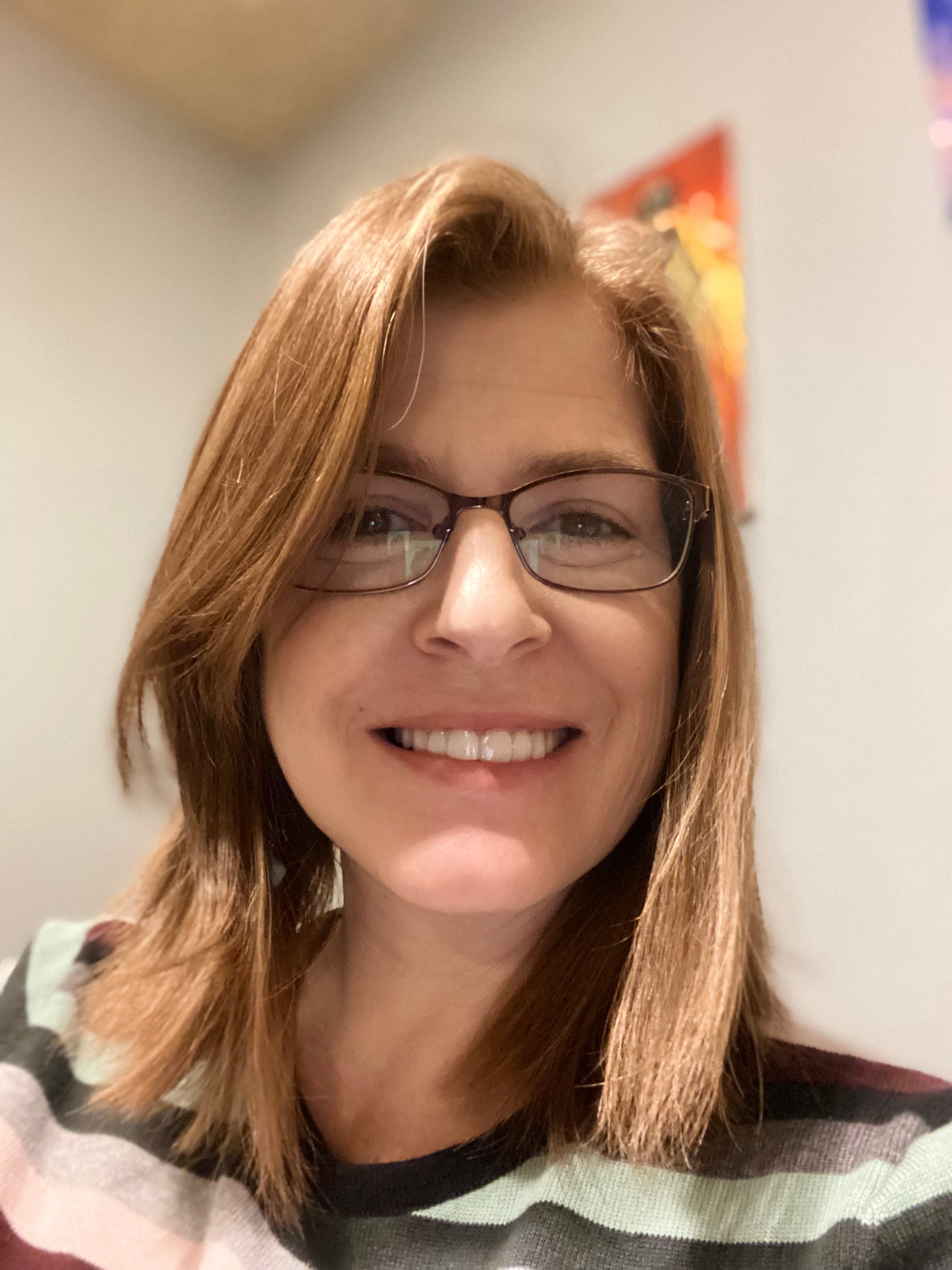 Person with glasses and a striped shirt in an indoor setting