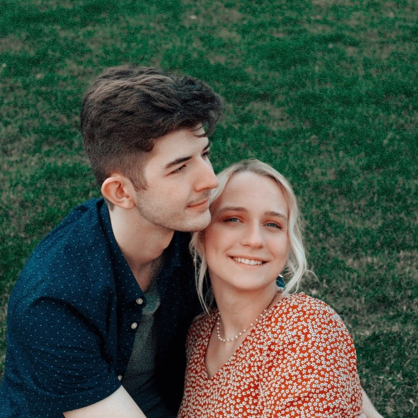 Man and woman sitting close together on grass