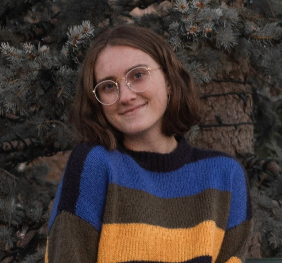 Person wearing a striped sweater in front of a tree