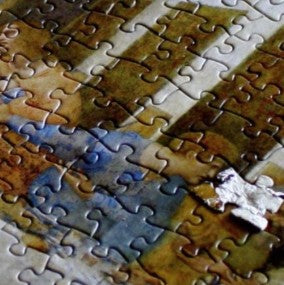 Close-up of a partially completed puzzle with various colors. One piece is damaged, but still fits