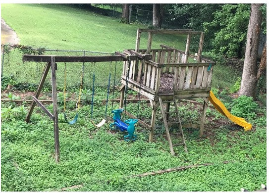 Wooden playset with a swing and slide in a grassy outdoor area